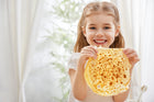 Gelukkige meid die een zelfgebakken pannenkoek vasthoudt, perfect voor het artikel 'Typisch Hollands: Pannenkoeken en poffertjes!'.